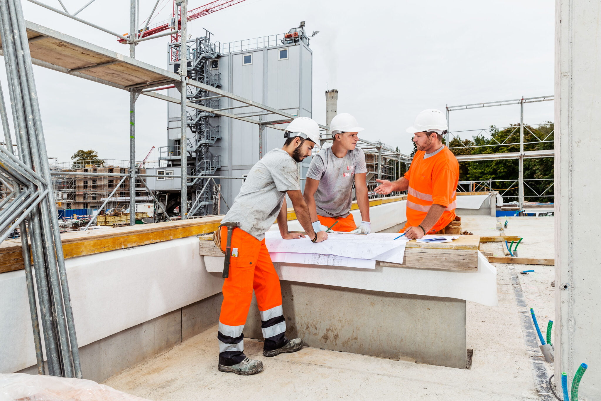 Lernender Maurer und Vorarbeiter im Gespräch mit dem Baupolier