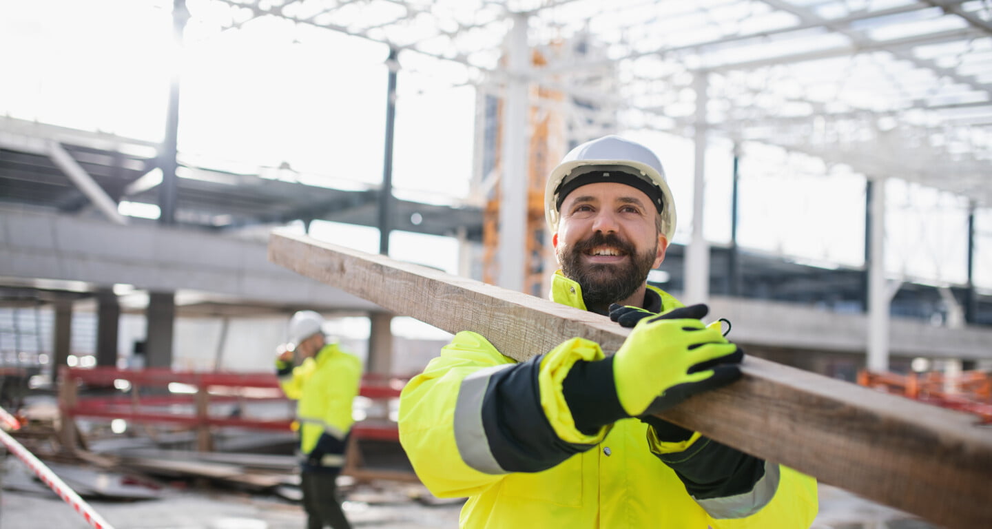 Bauarbeiter trägt Balken aus Holz