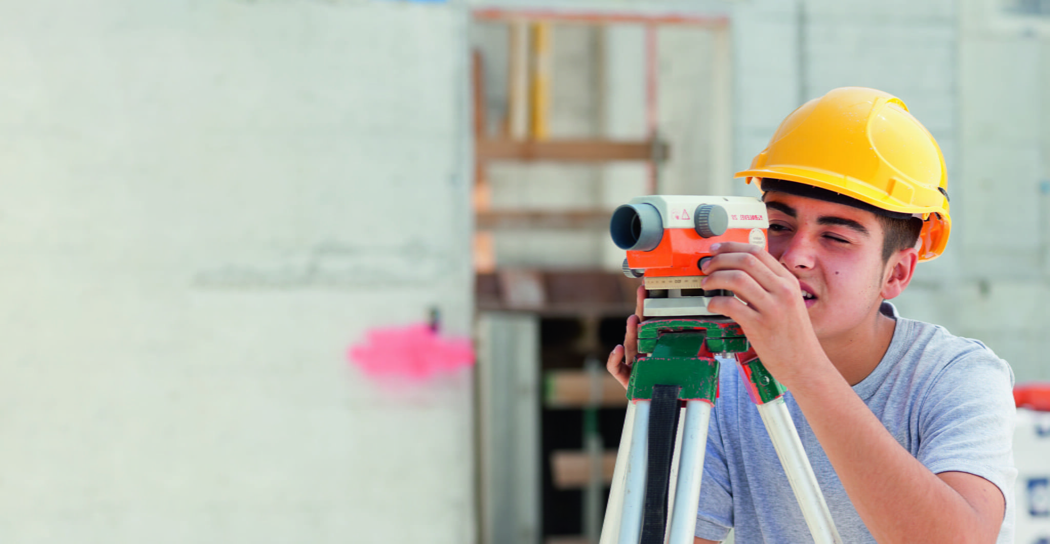 Lernender Maurer mit einem Nivelliergerät